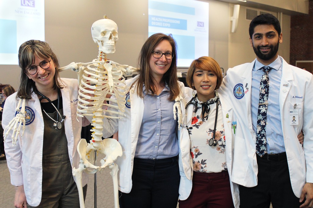 Four U N E osteopathic medicine students pose with an educational skeleton