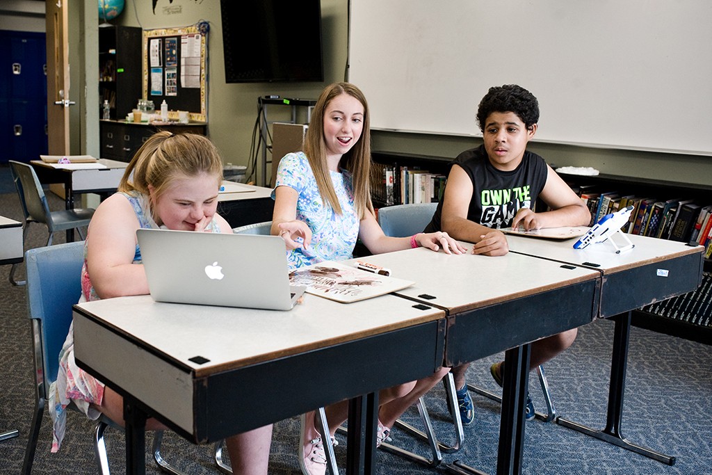 A student teaching two children in a classroom