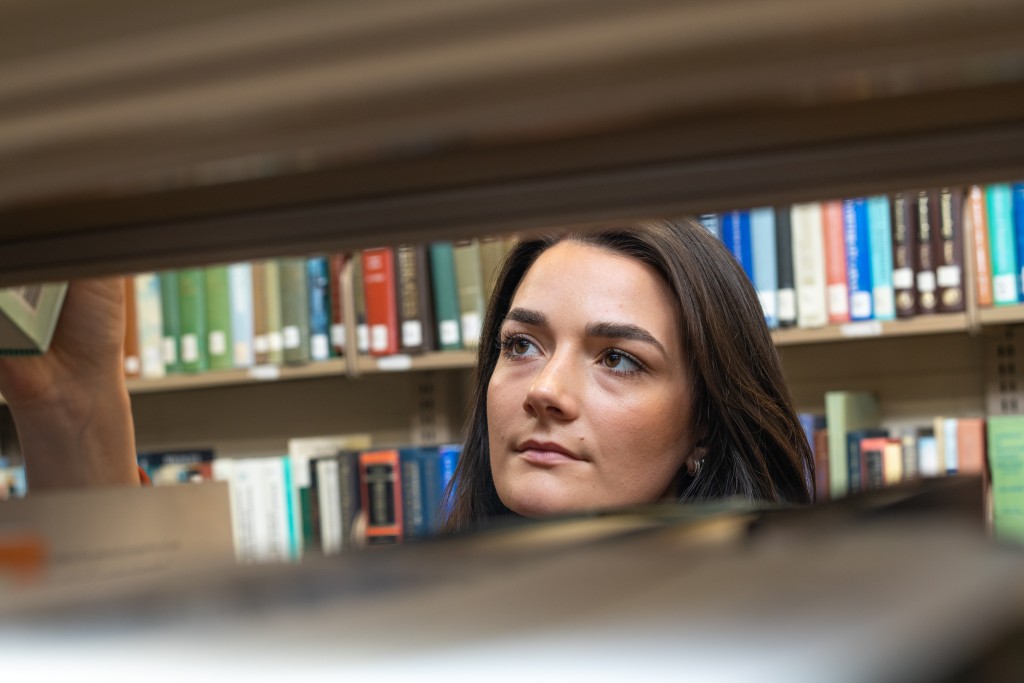 A u n e student searches a bookshelf