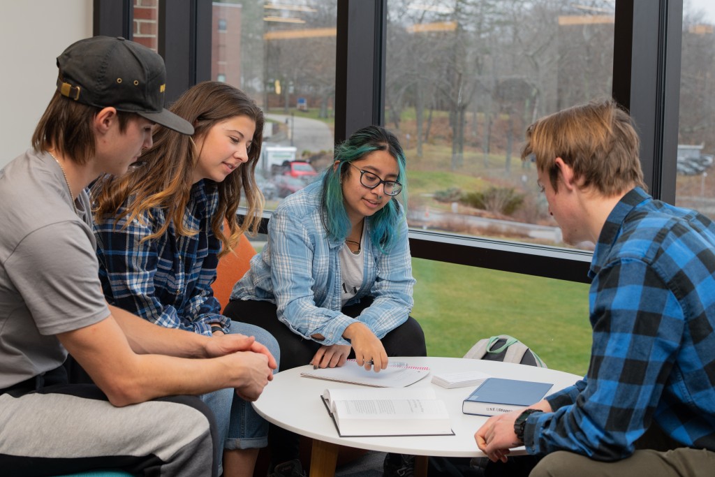 Four U N E students sit studying around a table in the Ripich Commons