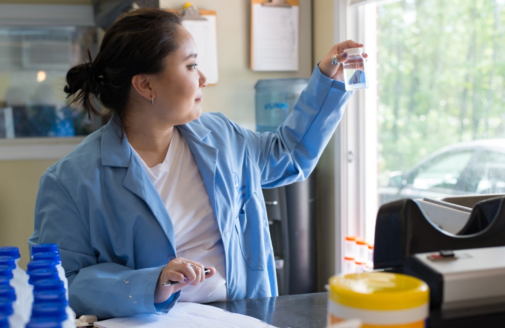 A student takes notes while holding up a small bottle of clear liquid