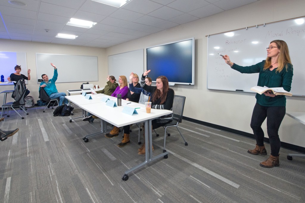 Students raise their hands to answer questions during a social justice class