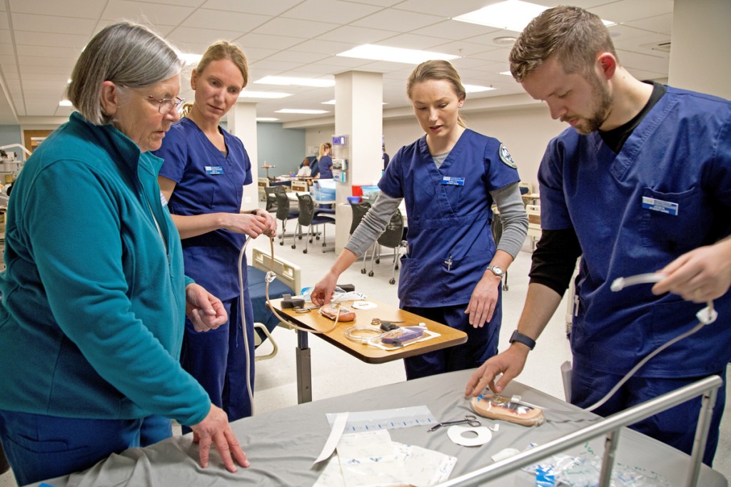 A nursing professor explains hospital tools to three students