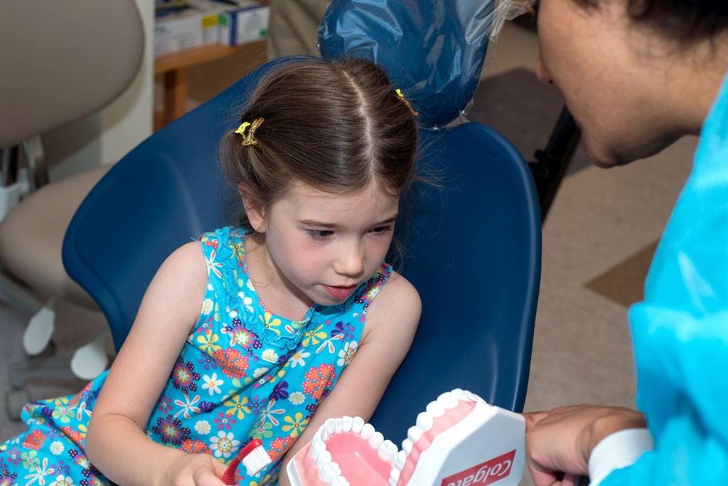 A child dental patient practices brushing on a model of teeth