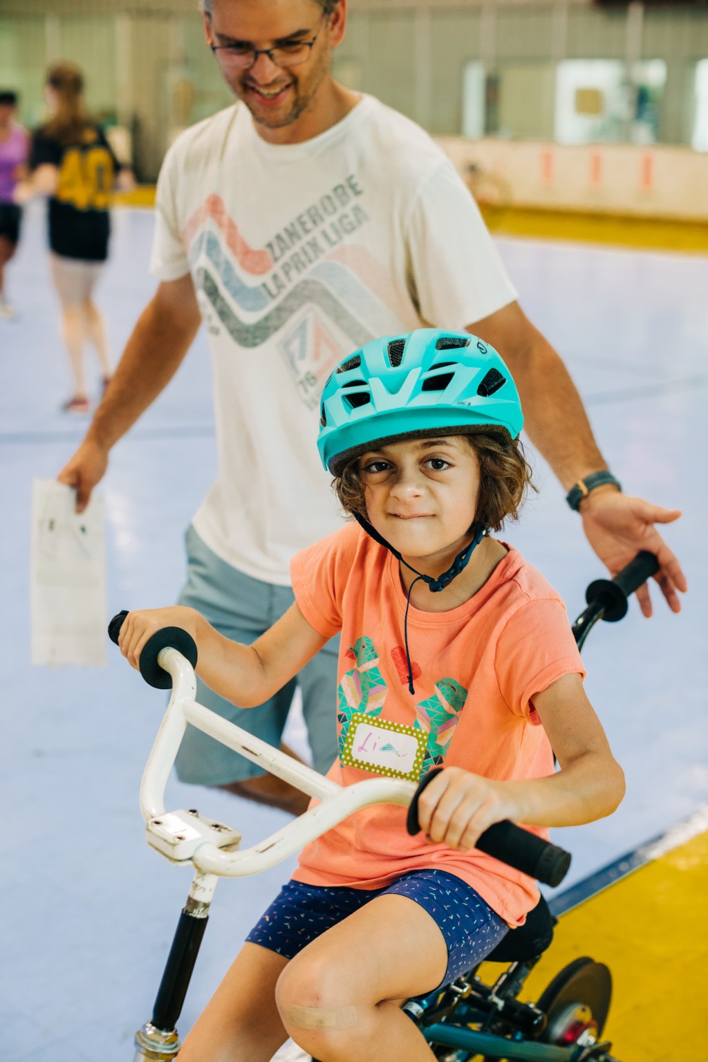 A young girl rides a bike inside a gymnasium