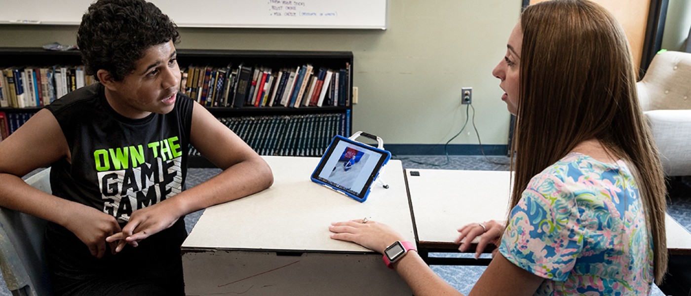 A U N E student shows an elementary school student how to use an i-pad