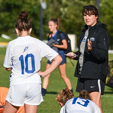 Women's soccer coach speaking with team members during practice