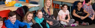 A student sits with children in a classroom