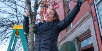 A student smiles as she hangs lights in front of Biddeford's City Theater