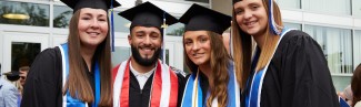 Four University of New England students pose in their graduation cap and gowns