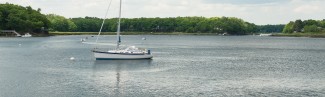 A boat sits in the center of a lake surrounded by a forest